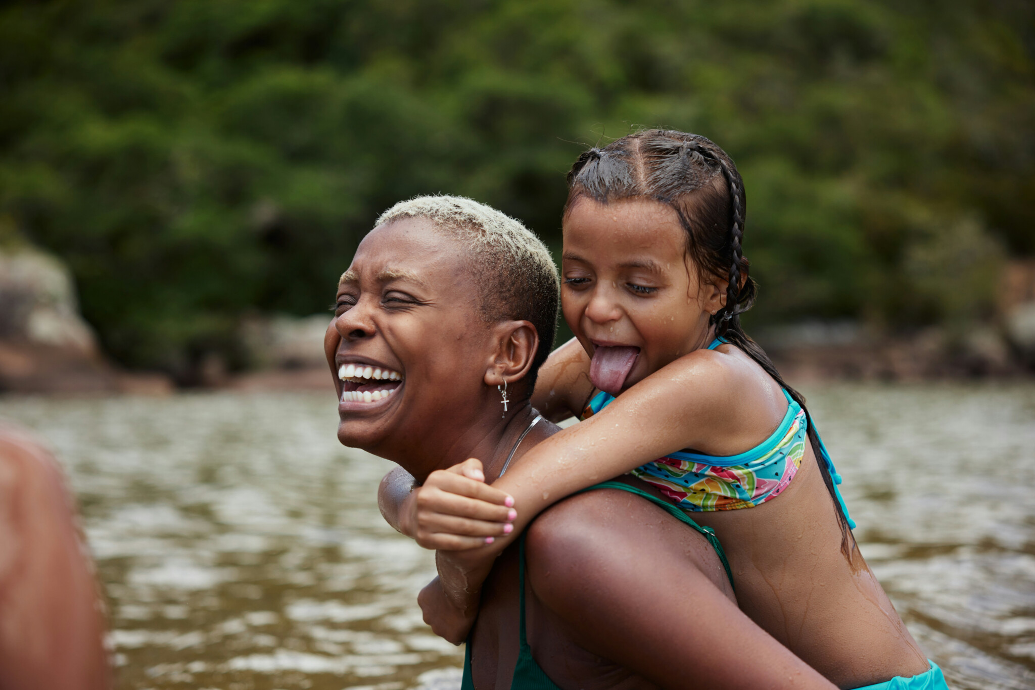 Group Of Humans, Healthspan Image, A woman of colour with a child on her back in bathing costume by the sea