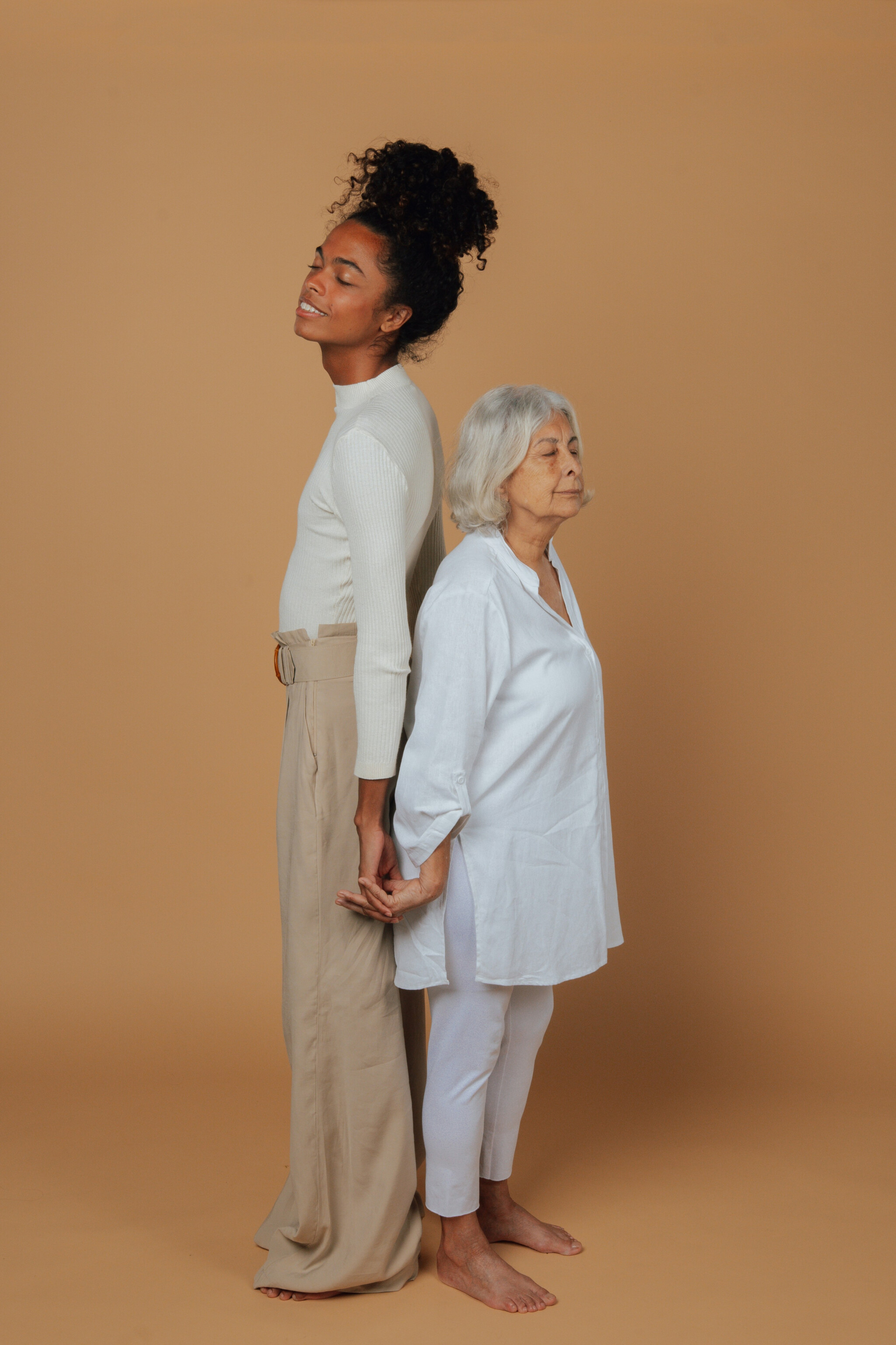 Group Of Humans, Healthspan Image, A young woman of colour and an older white woman stood back to back, one tall one short