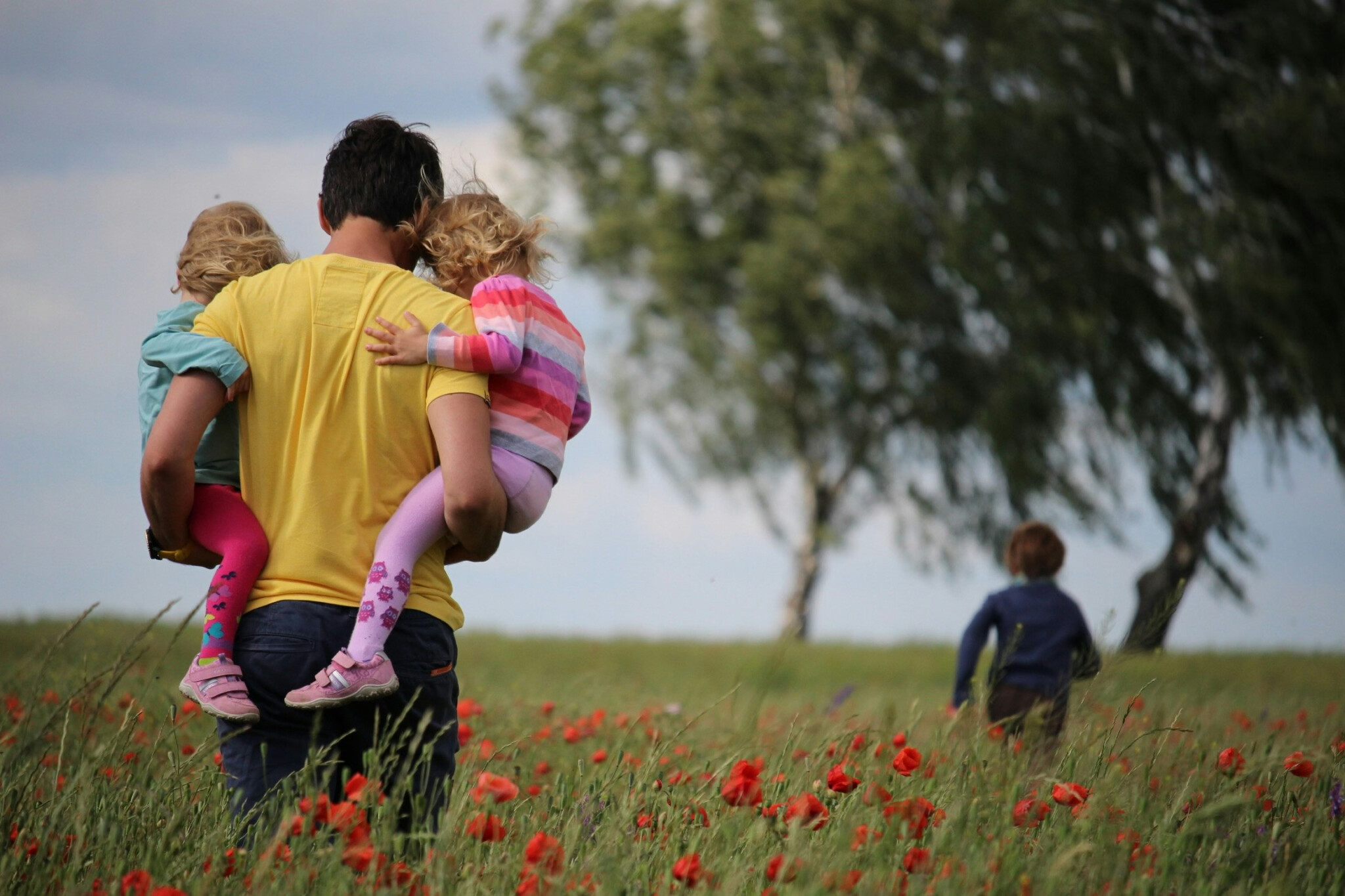 Group Of Humans, Healthspan Image, A father holding two young girls and a boy playing in the meadow